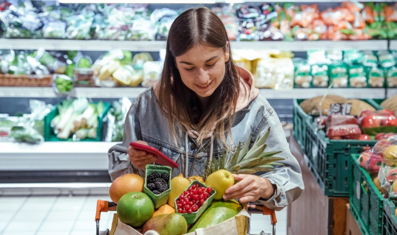 Vrouw checkt producten die ze gekozen heeft in de supermarkt op versheid en prijs