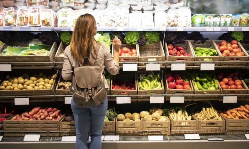 Vrouw maakt gezonde keuzes in supermarkt en koopt groenten en fruit in